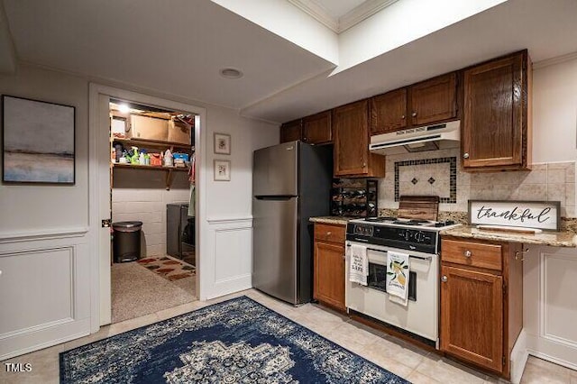 kitchen with freestanding refrigerator, crown molding, under cabinet range hood, and white electric stove