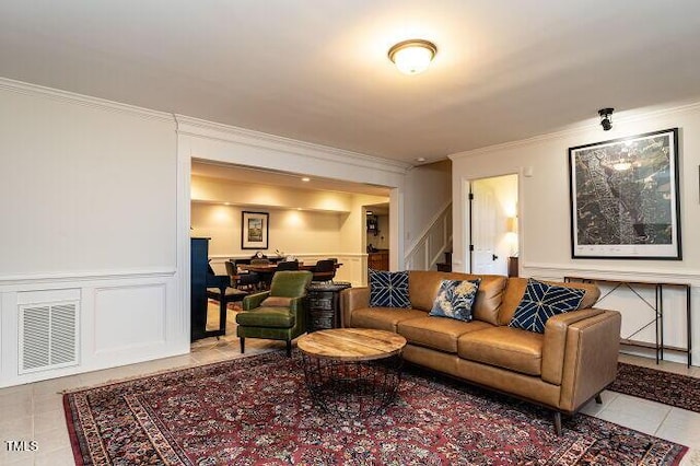 living room with light tile patterned floors, visible vents, ornamental molding, and stairs