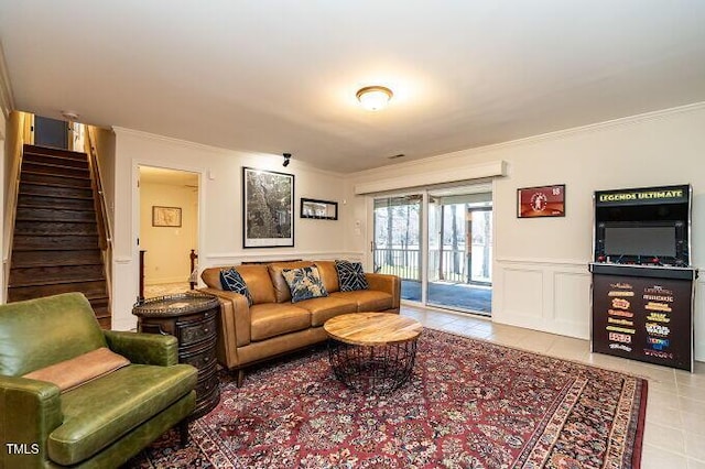 tiled living area with wainscoting, ornamental molding, stairs, and a decorative wall