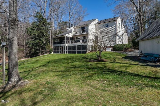 rear view of property with a lawn, a balcony, and a sunroom