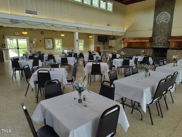 dining area featuring visible vents, speckled floor, and a towering ceiling