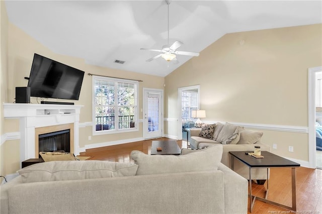 living room with wood finished floors, baseboards, a high end fireplace, ceiling fan, and vaulted ceiling