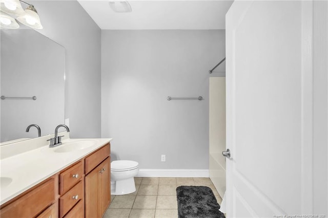 bathroom featuring tile patterned flooring, baseboards, toilet, double vanity, and a sink