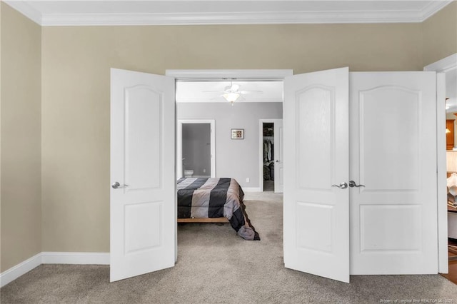 carpeted bedroom featuring connected bathroom, baseboards, a spacious closet, and crown molding