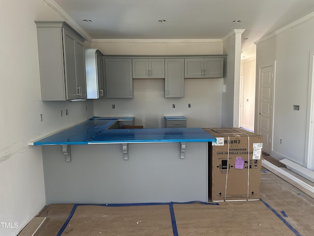 kitchen featuring gray cabinetry, crown molding, and a kitchen breakfast bar