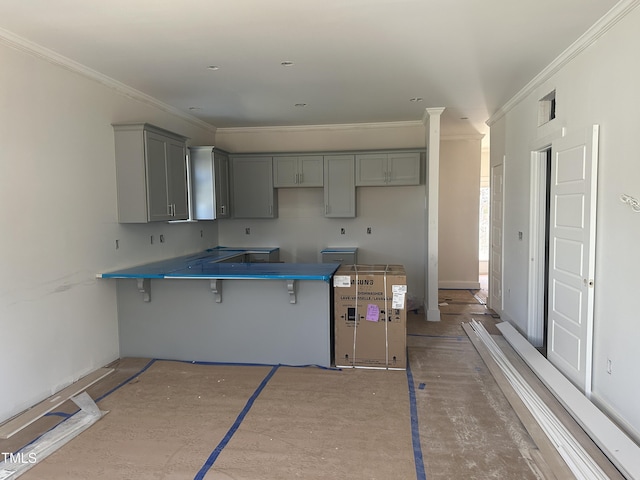 kitchen featuring crown molding, a breakfast bar area, visible vents, and gray cabinets