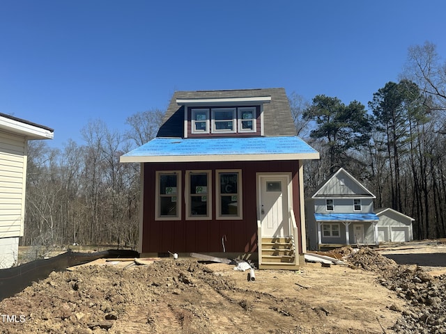 view of front of property featuring entry steps, an outdoor structure, a garage, and board and batten siding