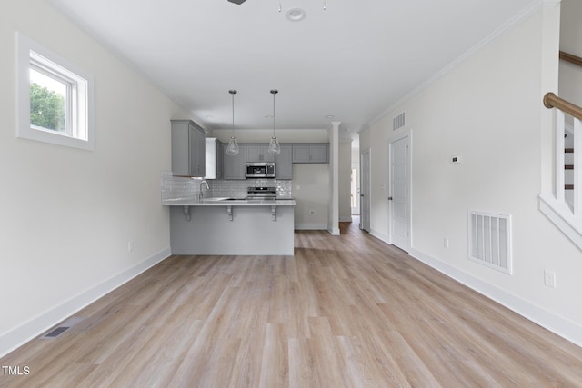 1448C Maplewood Dr, Durham, NC 27704 - kitchen featuring gray cabinets, a peninsula, a breakfast bar area, stainless steel appliances, and light countertops