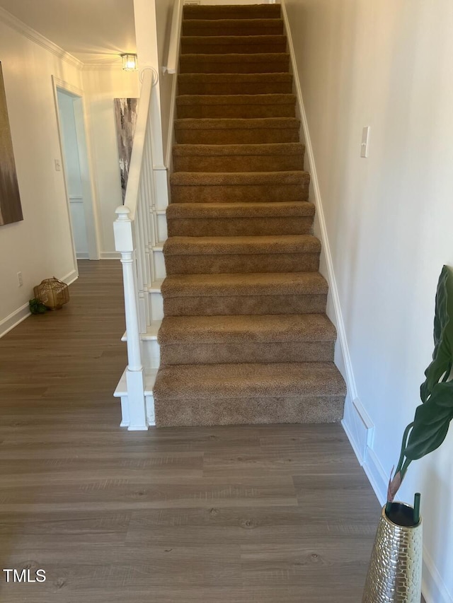 staircase featuring baseboards and wood finished floors