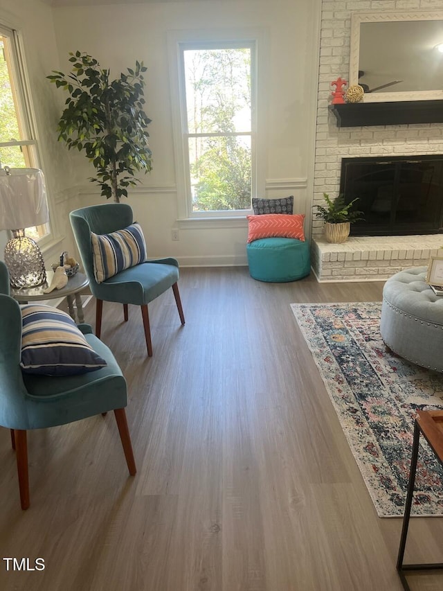 living area with a fireplace, wood finished floors, and baseboards