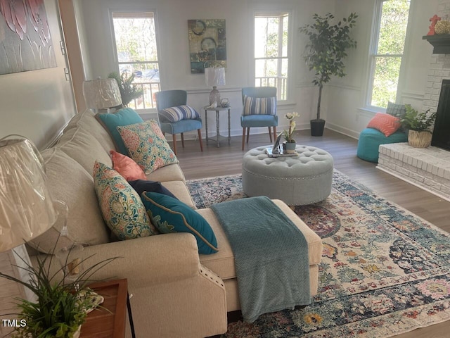 living area with a brick fireplace, wood finished floors, and a wealth of natural light