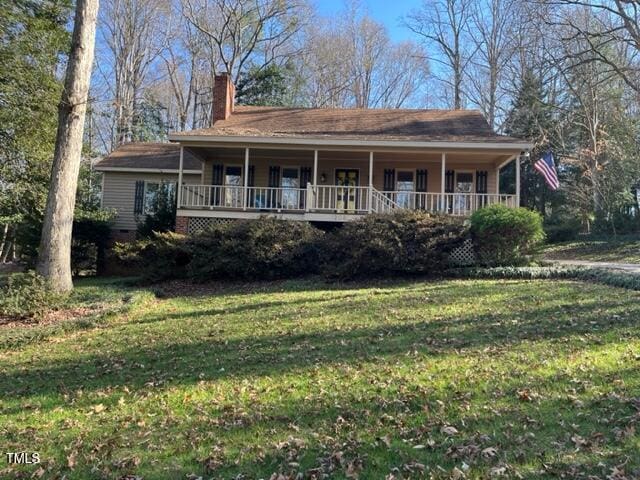 view of front of home featuring crawl space, a chimney, a porch, and a front yard