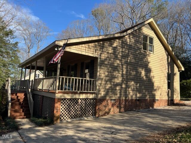 view of side of home featuring stairs, covered porch, driveway, and crawl space