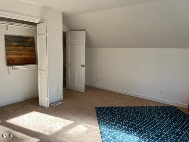 additional living space with baseboards, visible vents, lofted ceiling, and carpet floors