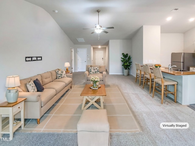 carpeted living room with a sink, visible vents, and ceiling fan