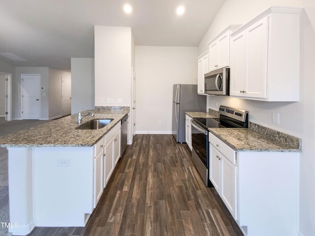 kitchen featuring a sink, white cabinetry, appliances with stainless steel finishes, a peninsula, and dark wood-style flooring