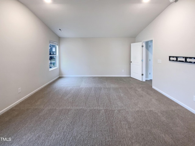 empty room featuring visible vents, baseboards, carpet, and lofted ceiling