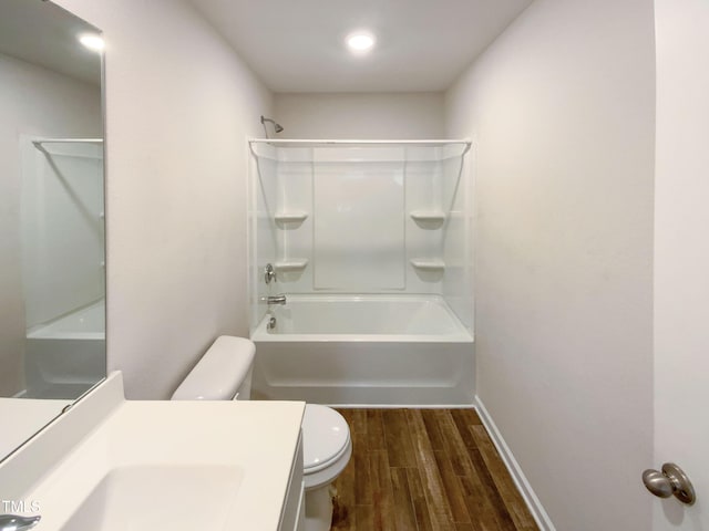 full bathroom with baseboards, toilet, vanity, wood finished floors, and washtub / shower combination