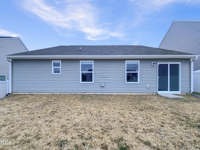 back of house with a lawn and roof with shingles