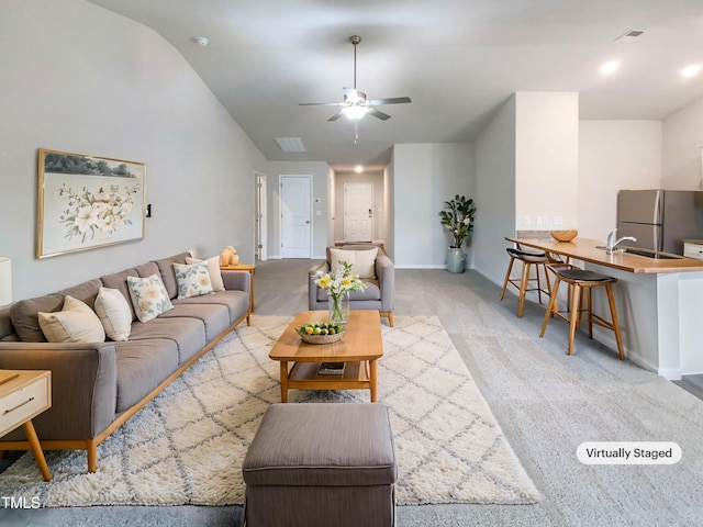 living area with visible vents, baseboards, light colored carpet, vaulted ceiling, and a ceiling fan