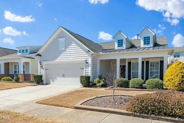 view of front of home with a garage, metal roof, concrete driveway, and a standing seam roof