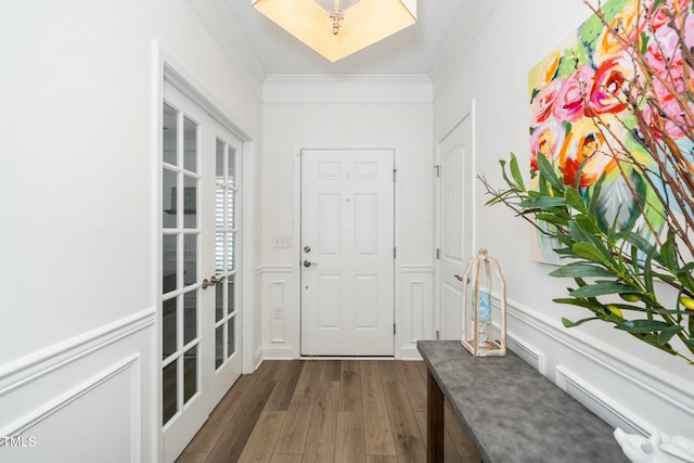 entrance foyer with dark wood-type flooring, french doors, a decorative wall, wainscoting, and crown molding