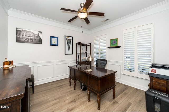 office area featuring visible vents, ceiling fan, a wainscoted wall, ornamental molding, and wood finished floors