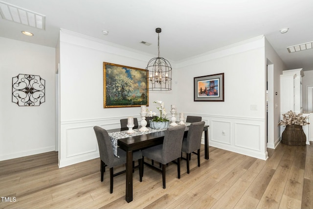 dining area with light wood finished floors, visible vents, and a decorative wall