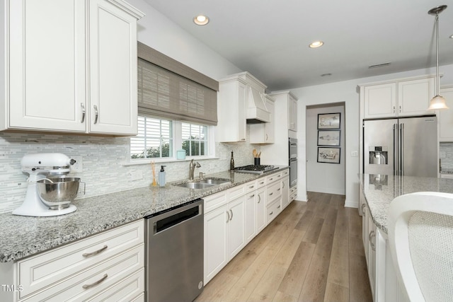 kitchen featuring light wood-style flooring, a sink, backsplash, white cabinetry, and stainless steel appliances