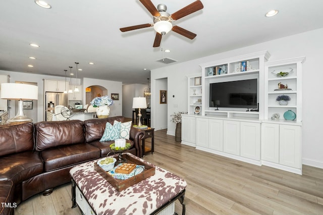 living area with arched walkways, visible vents, recessed lighting, and light wood-style floors