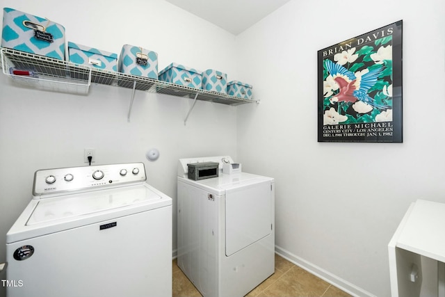 laundry area with washing machine and clothes dryer, laundry area, baseboards, and light tile patterned floors