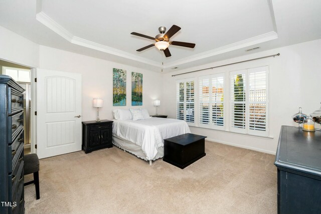 bedroom featuring a raised ceiling, light carpet, and ornamental molding