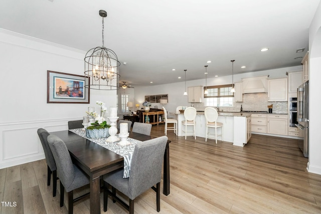 dining space with wainscoting, recessed lighting, light wood-style flooring, a decorative wall, and a ceiling fan