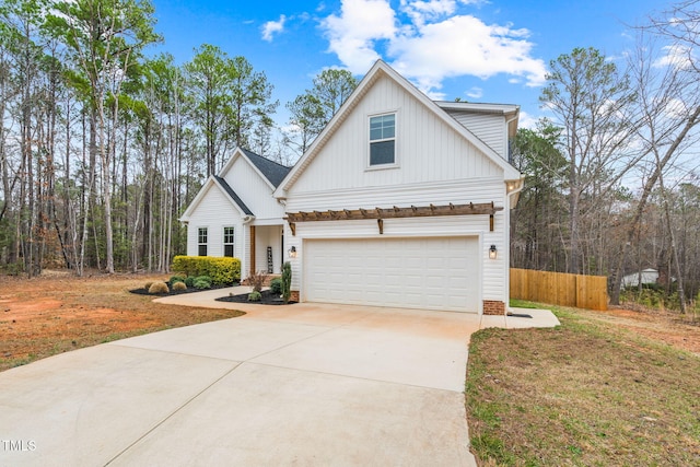 modern farmhouse style home with driveway, board and batten siding, and fence