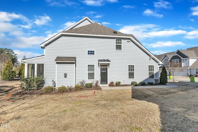 rear view of property featuring a lawn and roof with shingles