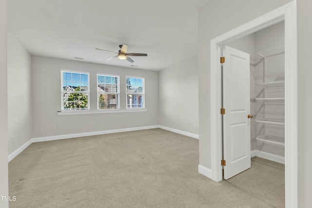 empty room with light carpet, visible vents, a ceiling fan, and baseboards