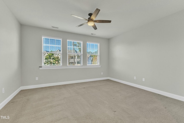 spare room with a ceiling fan, visible vents, carpet floors, and baseboards