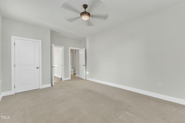 unfurnished bedroom with baseboards, light carpet, and connected bathroom