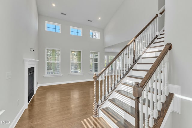 stairway with plenty of natural light, baseboards, a glass covered fireplace, and wood finished floors