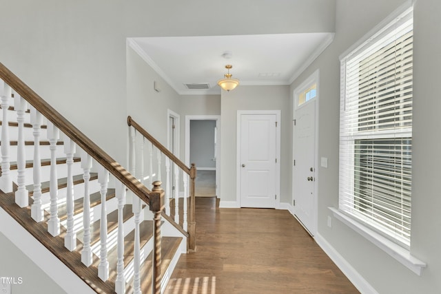 foyer entrance featuring visible vents, ornamental molding, wood finished floors, baseboards, and stairs