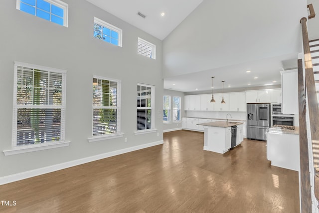 kitchen with dark wood-style floors, visible vents, a kitchen island with sink, a sink, and appliances with stainless steel finishes