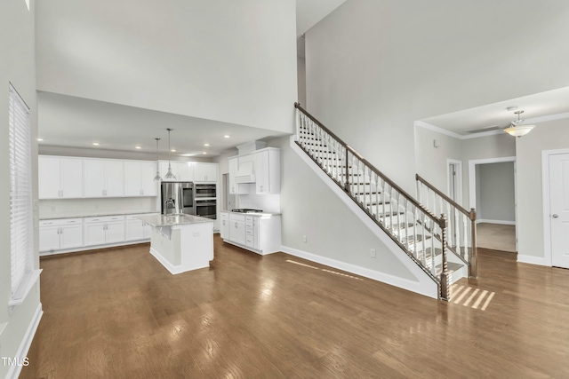 kitchen with a sink, stainless steel appliances, light countertops, a towering ceiling, and dark wood-style flooring