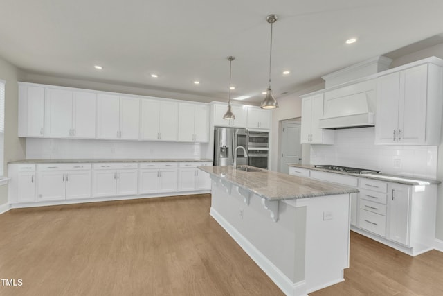 kitchen with stainless steel appliances, light wood-style flooring, white cabinets, and custom range hood