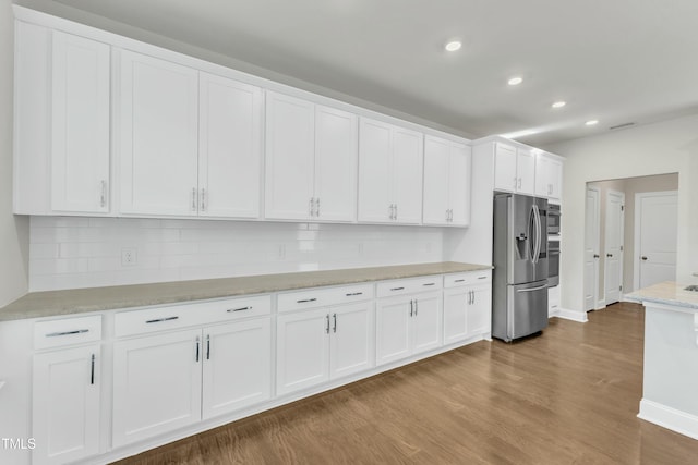 kitchen with recessed lighting, dark wood-style flooring, stainless steel appliances, decorative backsplash, and white cabinetry