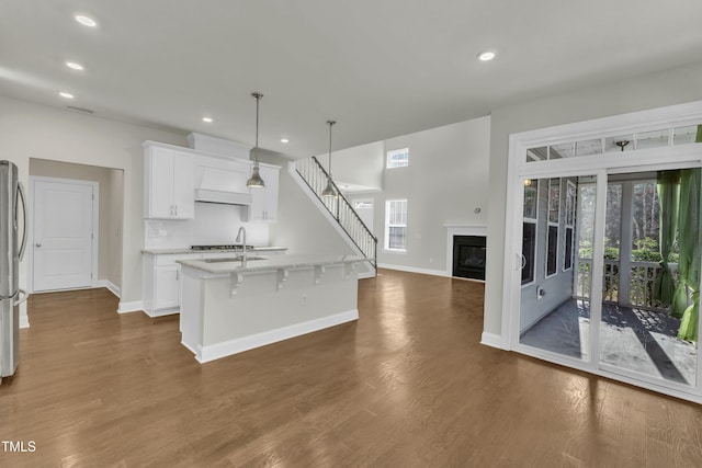 kitchen featuring a healthy amount of sunlight, a center island with sink, dark wood-style flooring, and white cabinets