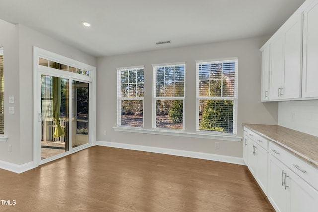 unfurnished dining area featuring dark wood-type flooring, recessed lighting, baseboards, and visible vents