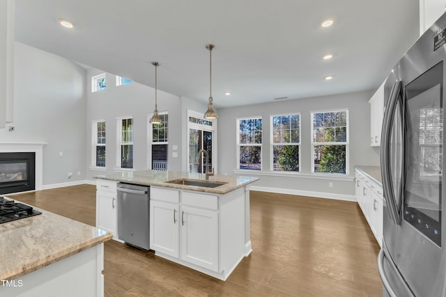 kitchen with dark wood-style floors, a glass covered fireplace, white cabinets, stainless steel appliances, and a sink