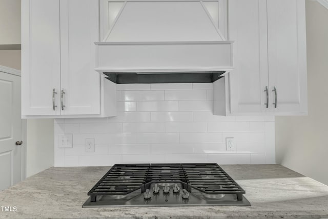 kitchen featuring decorative backsplash, custom exhaust hood, stainless steel gas stovetop, and white cabinetry