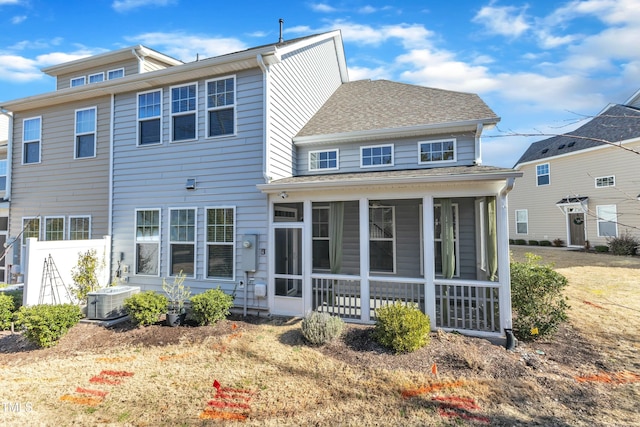 back of house with central air condition unit, a sunroom, and a shingled roof