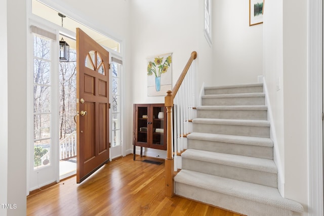 foyer with stairs, wood finished floors, visible vents, and a healthy amount of sunlight